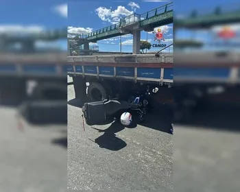 Moto vai parar embaixo de caminhão após acidente em via