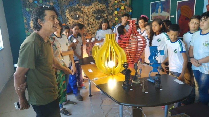 Albério Carvalho (esq.) acompanha visitantes na exposição em Arapiraca