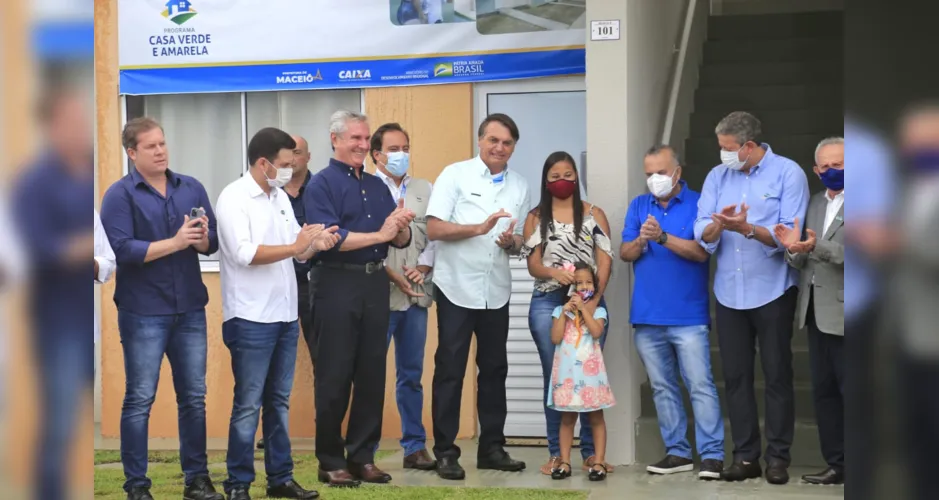 Acompanhado da comitiva, Bolsonaro entrega chaves a moradora de residencial