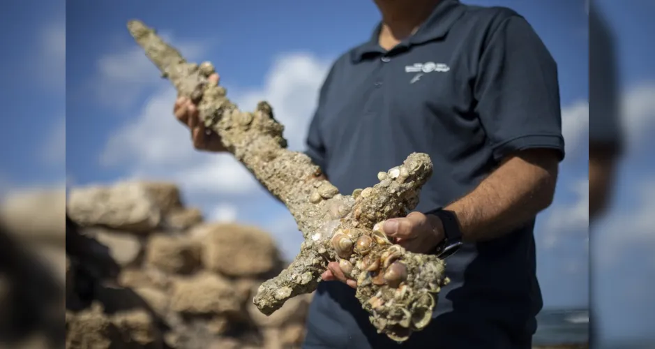 Jacob Sharvit, diretor da Unidade de Arqueologia Marinha da Autoridade de Antiguidades de Israel, segura espada de um metro de comprimento que foi encontrada no Mar Mediterrâneo