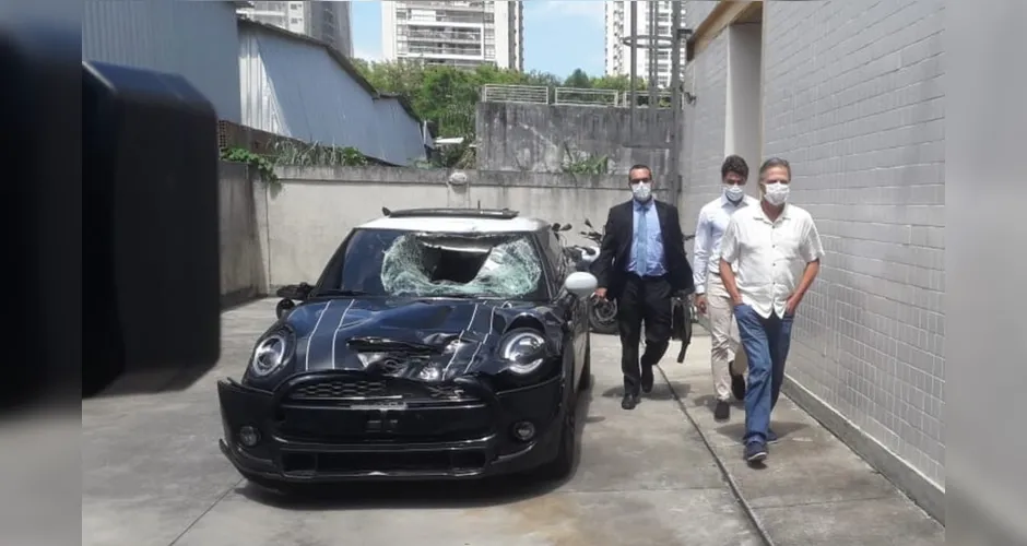 Marcinho, ex-Botafogo, e o pai Sergio Lemos de Oliveira, saem da delegacia ao lado do carro do acidente