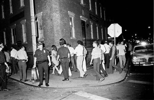Three police officers kept a tight rein on a crowd to keep them on the sidewalks and off the streets at the corner of Waverly Place and Christopher Steet, half a block from the Stonewall Inn. The image was shot by Times photographer Larry Morris on the evening of Wednesday, July 2, 1969, five nights after a raid on the Stonewall Inn, a nightclub on Christopher Street popular among gay men and lesbians, touched off the disturbances. The Stonewall uprising that began 40 years ago this month has come to be seen as a defining event in the development of the gay rights movement. (Larry Morris/The New York Times)